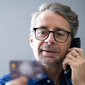 man on phone looking at credit card