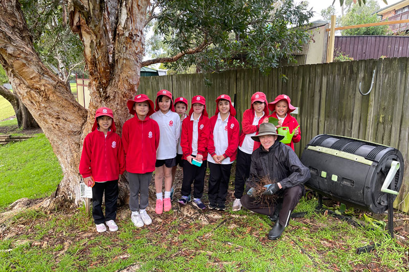 group of school kids and teacher with compost bin