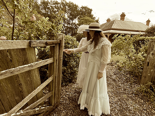 2 females dressed up standing near wooden gate