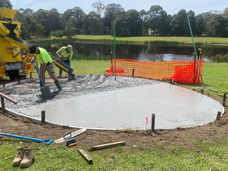 workers pouring concrete from truck onto slab