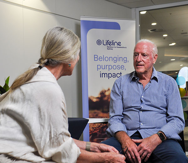 male chatting to female in front of Lifeline sign