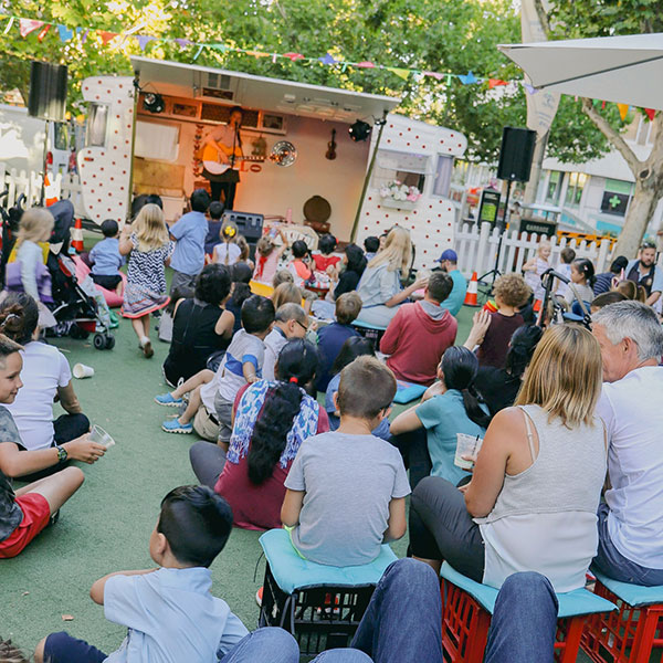 crowd sitting infront of truck watching performer