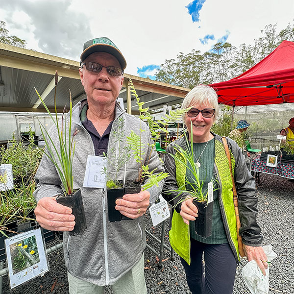 man and woman holding plants