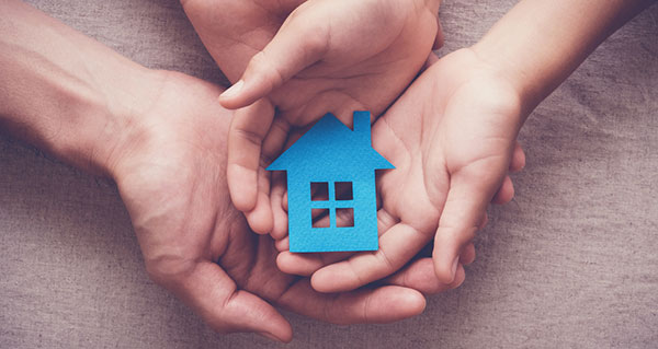 Adult and child hands holding paper house