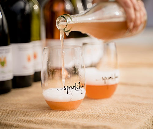 hand pouring bottle of wine into glasses